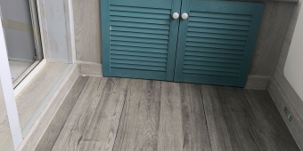 Отделка балкона ламинатом нескольких цветов. Установка стола для вечерних посиделок, шкафчика для хранения и сидушки. Подключение освещения. Утепление передней части.